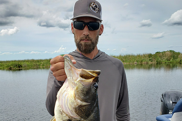 Bass fisherman holding a large mouth bass on either Stick Marsh or Headwaters Lake in Fellsmere, FL